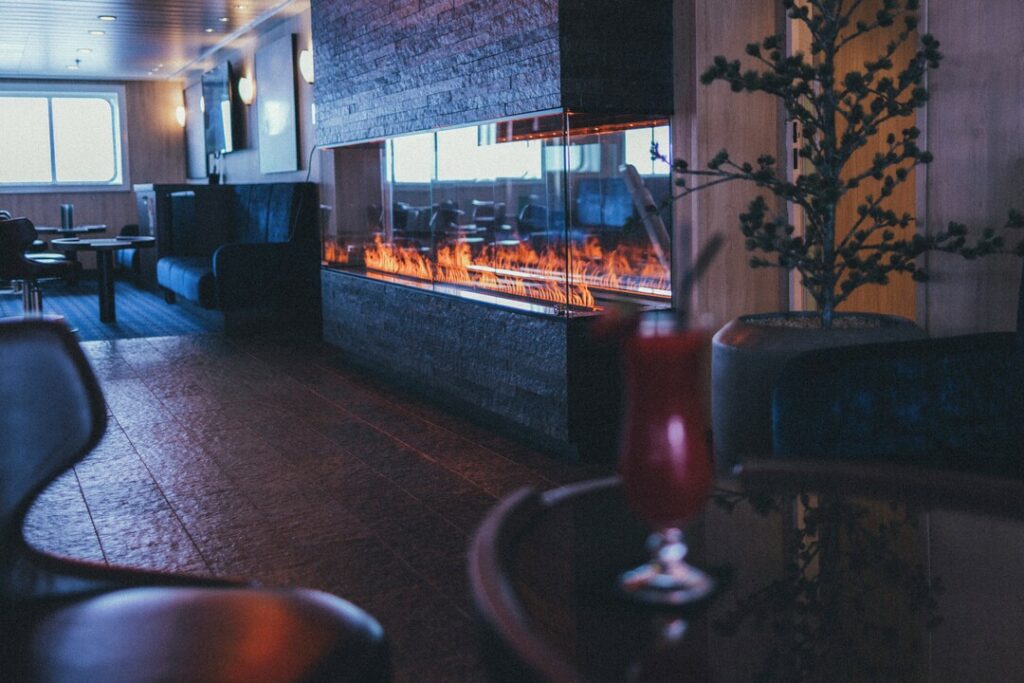 Explorer Bar MS Spitsbergen Lounge Sessel und moderne Feuerstelle mit gläserner Umrandung