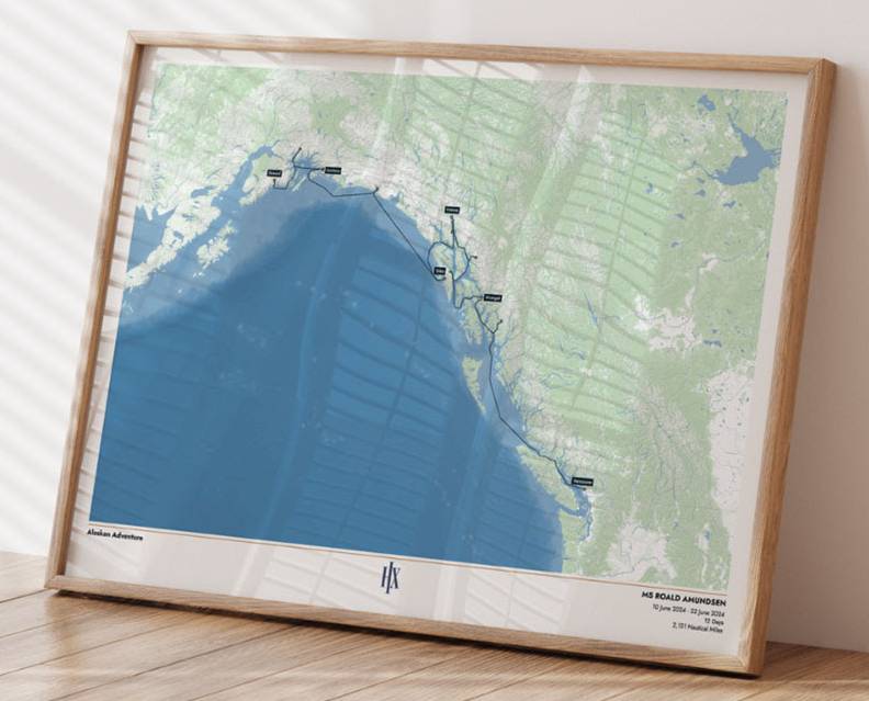 Personalisierte Seekarte in Holzrahmen, stehend auf einem Tisch – zeigt eine individuelle Reiseroute entlang einer Küste, erstellt von HX Hurtigruten Expeditions.
