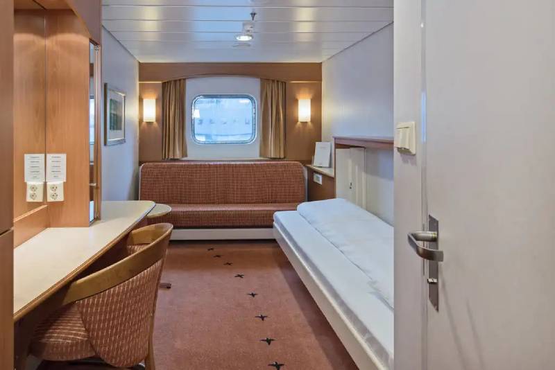 Polar Außenkabine an Bord der MS Midnatsol, mit einem Einzelbett, einem Schreibtisch mit Stuhl und einem Fenster ausgestattet.