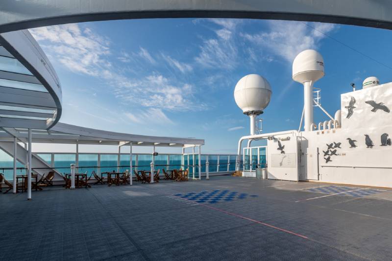 Das großzügige Außendeck an Bord der MS Midnatsol bietet offene Sitzbereiche mit Meerblick, überdachte Zonen und technische Ausstattung wie Radarkuppeln – ideal zum Entspannen an Deck.