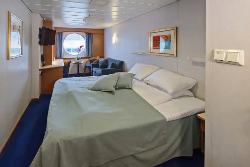 Mini-Suite auf dem Mittel- oder Oberdeck (Q2) mit Doppelbett, großem Fenster, Sitzecke und maritimer Einrichtung an Bord der MS Midnatsol