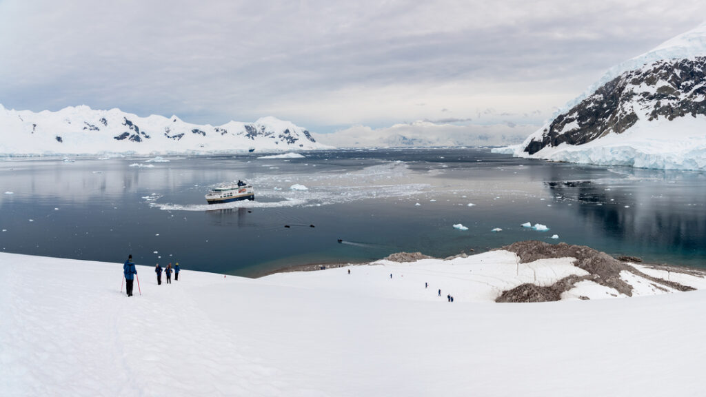Expeditionsschiff MS Fram in einer verschneiten Bucht bei Neko Harbour in der Antarktis, umgeben von Eis und Bergen.